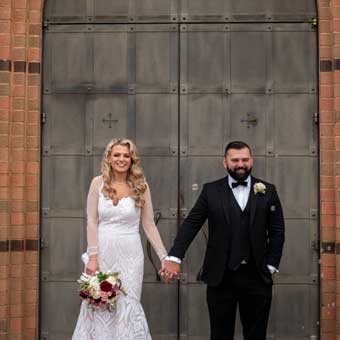 Bride and Groom holding hands standing in front of the closed church doors.