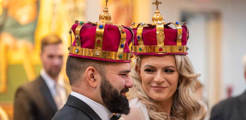 Bride and Groom at the church altar with king and queens crowns.