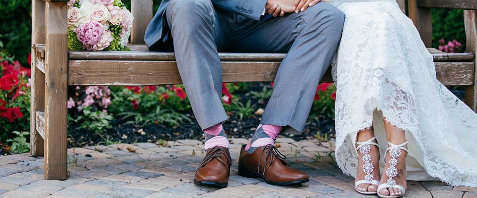 Bride and groom sitting on a bench shoes showing only. 