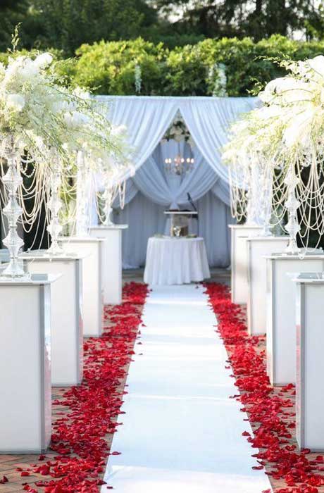 Outdoor ceremony setup leading up to the altar with tall centerpieces and red rose petals along the 