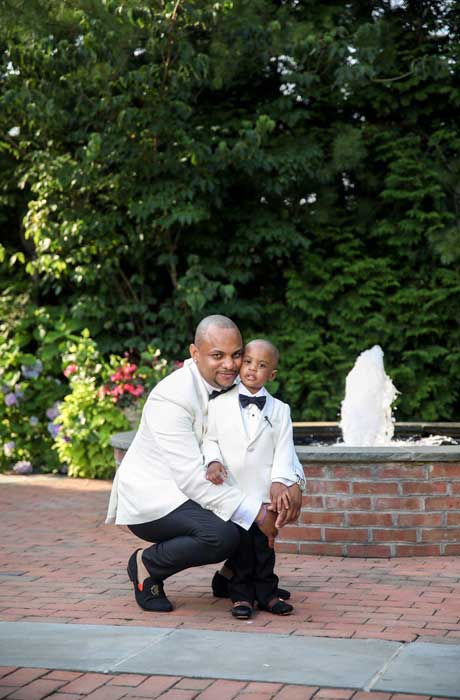 Groom and son in white and black tuxedos. 
