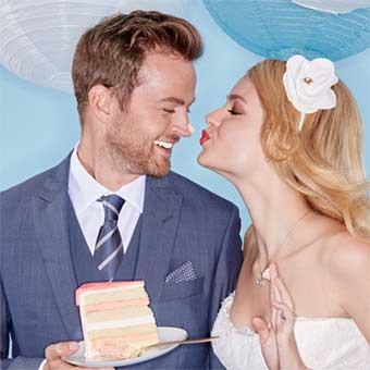 Bride and Groom eating a piece of cake with frosting on groom's nose.