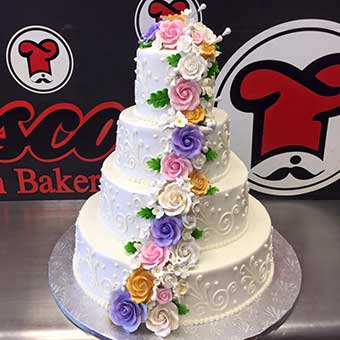 4 tier wedding cake with colorful flowers cascading from top to bottom.