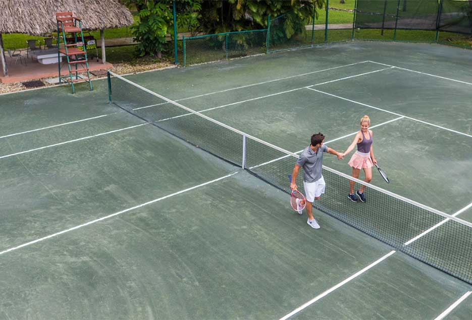 Couple playing tennis at Couples Resorts.