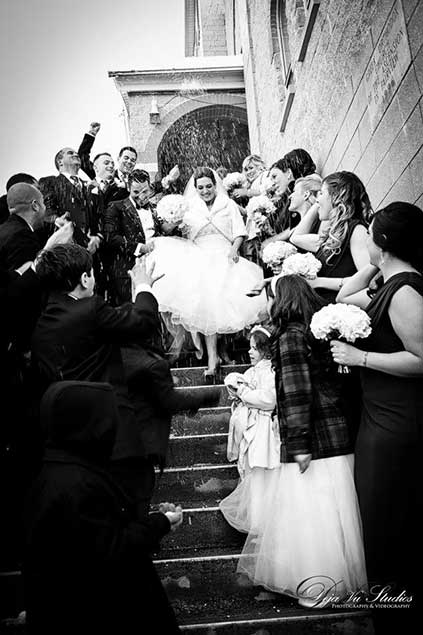 Black and white image of bride and groom coming out of church after being married