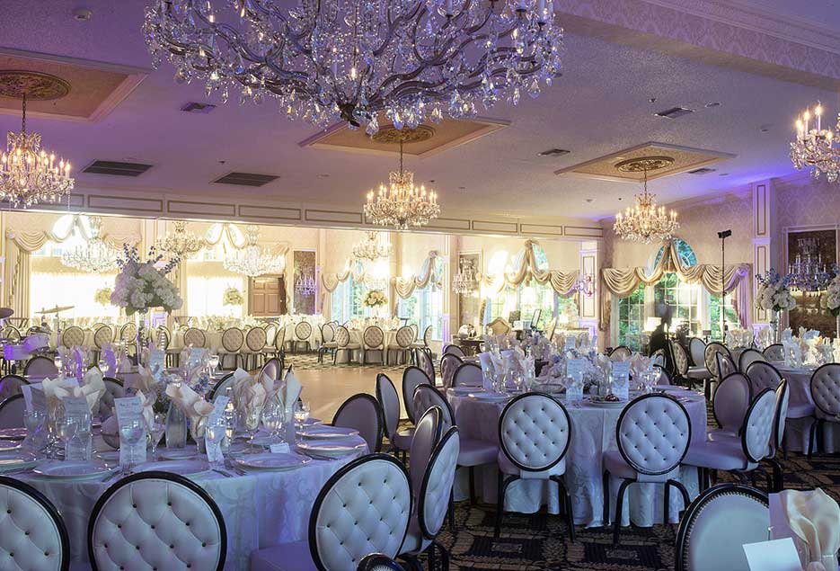 White wedding theme setup in ballroom with chandeliers. 