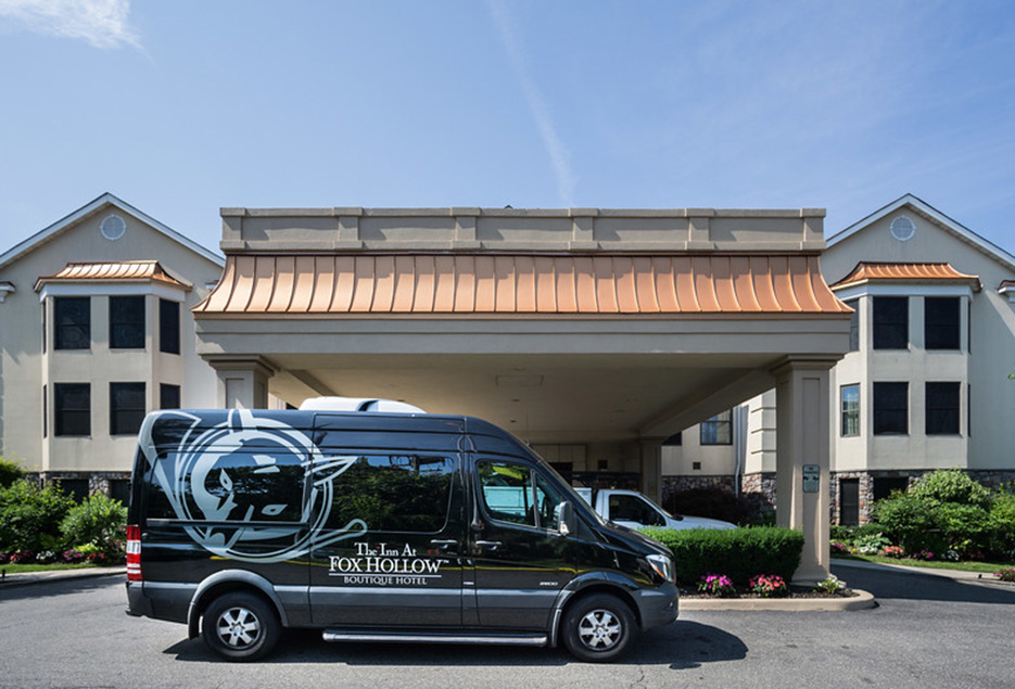 Exterior entrance of The Inn at Fox Hollow with hotel black van.