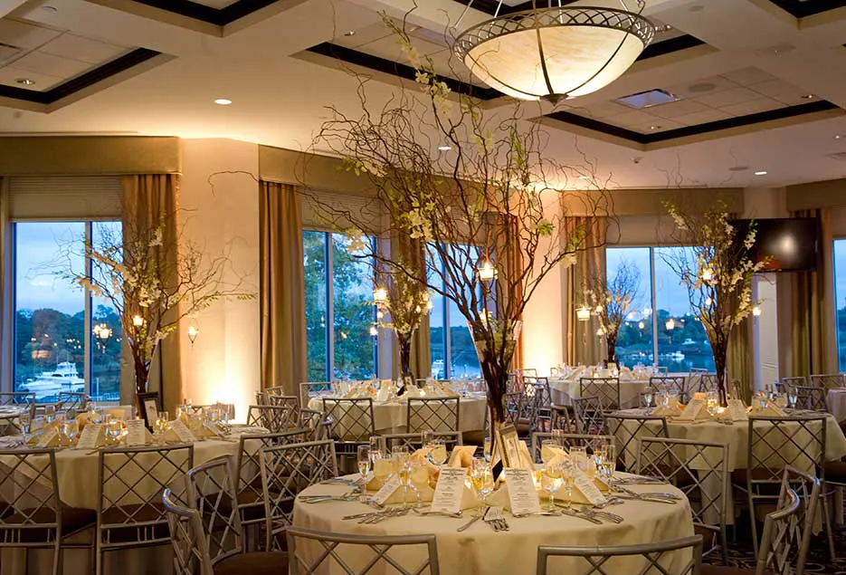 Reception area with simple white tablecloths and branches with lights as centerpieces.