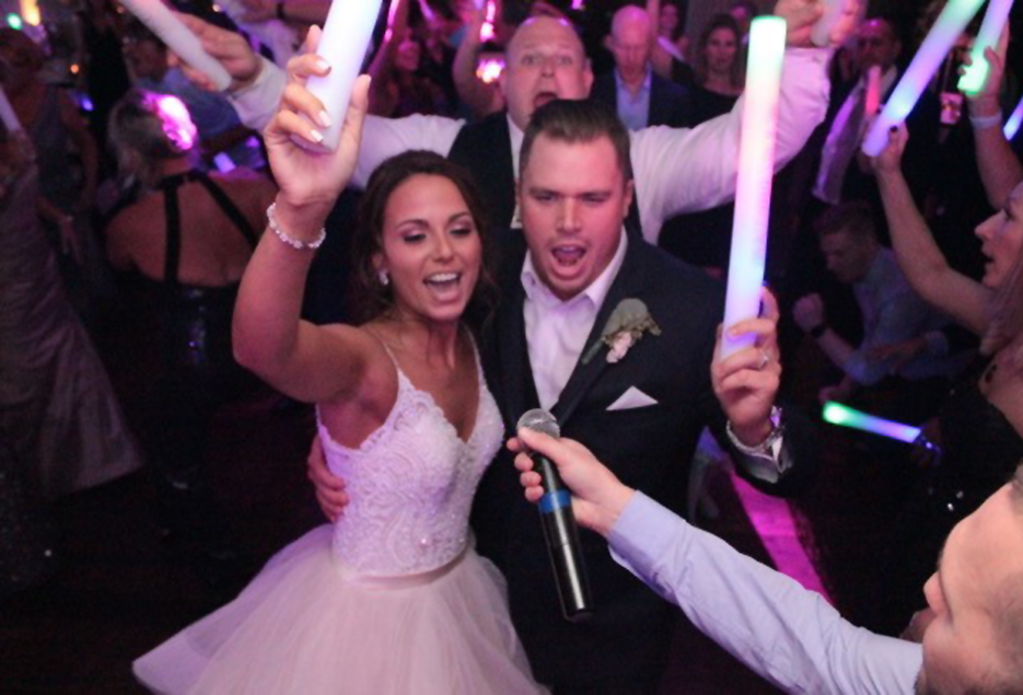 Bride and groom sing into mic while dancing on the dance floor.