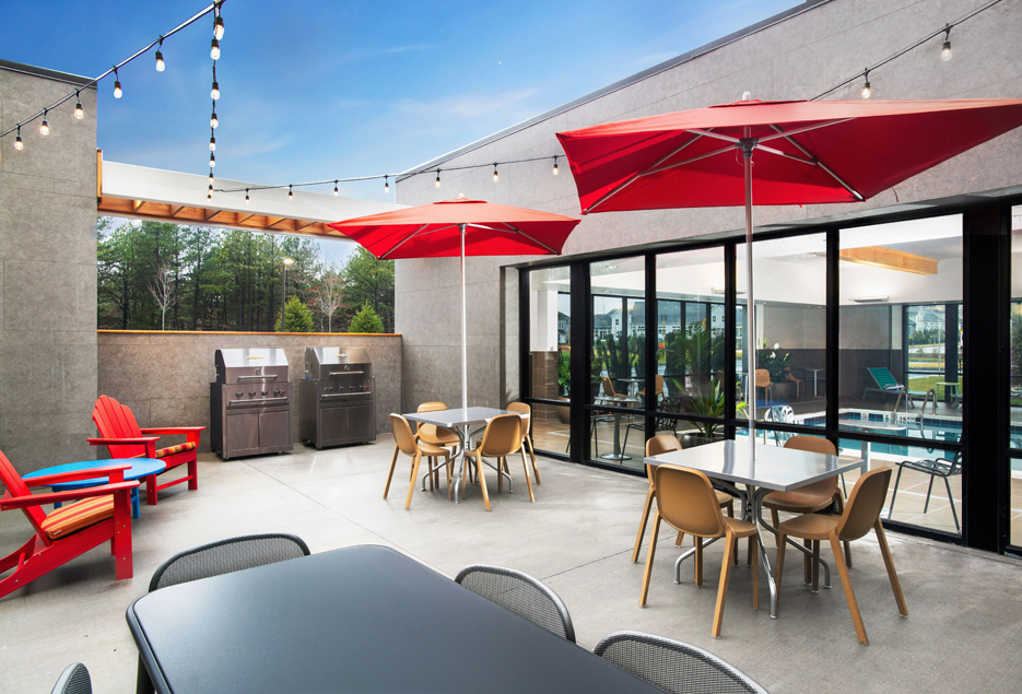 Outdoor patio area with grills, tables, seating, and red umbrellas.