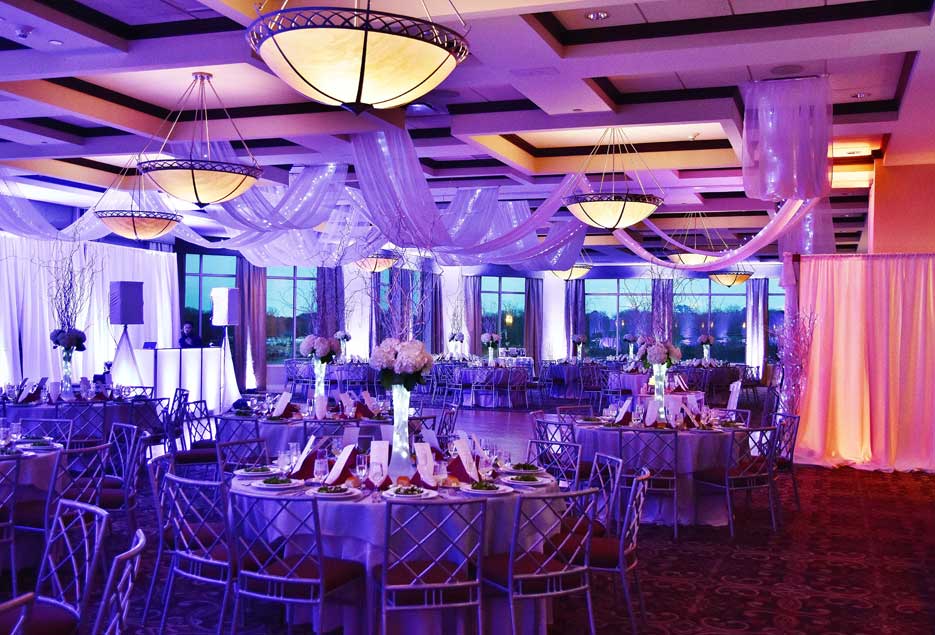 The reception ballroom setup with purple and pink uplighting. 