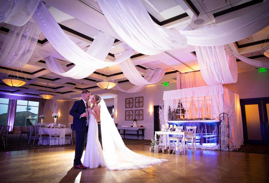 Bride and groom dancing in ballroom with uplighting. 
