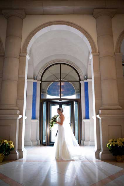 Bride standing  near the main entrance holding her flowers. 