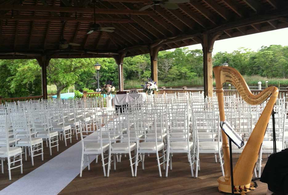 Outdoor ceremony setup with harp in the background. 