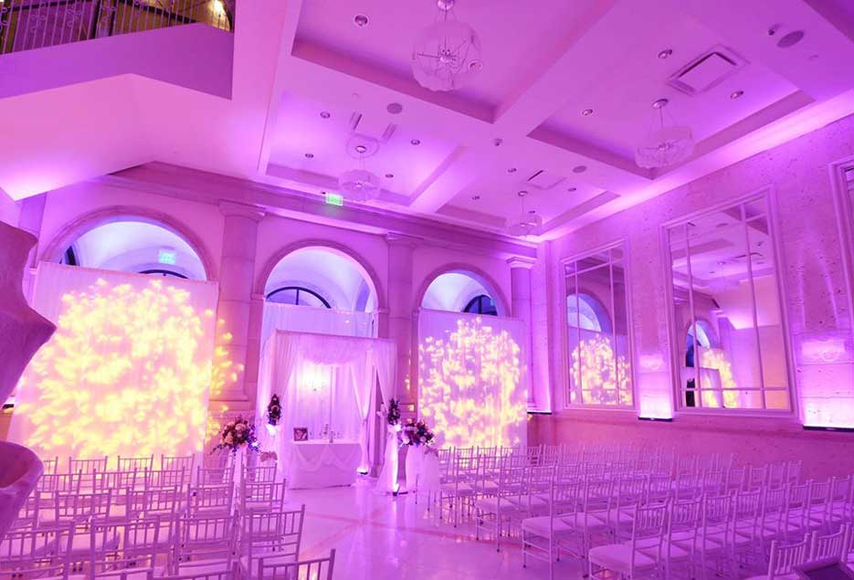 Beautiful indoor ceremony setup with pink uplighting. 