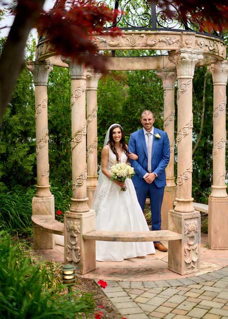 Bride and groom standing outside under a beautiful gazebo. 