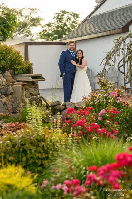 A couple standing by flowers in the garden of the Riviera Waterfront  Mansion. 