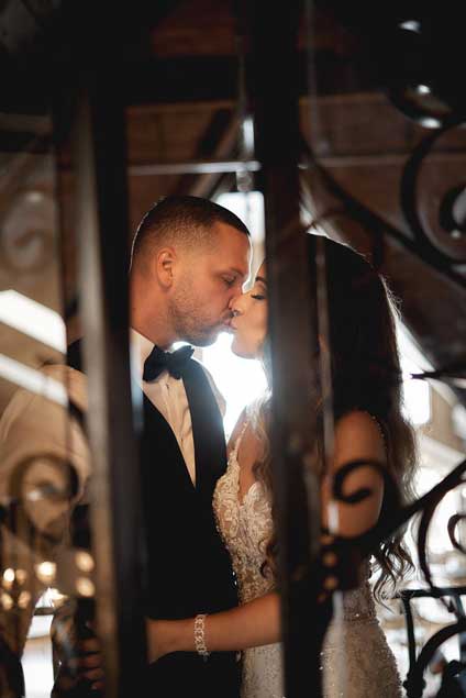A wedding couple exchanging kisses by a window. 
