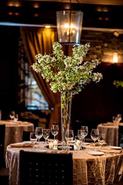 A private event table setup with tall flower centerpieces on the tables. 