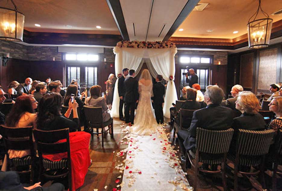 A private indoor wedding ceremony with a couple exchanging their  vows as guests look on. 