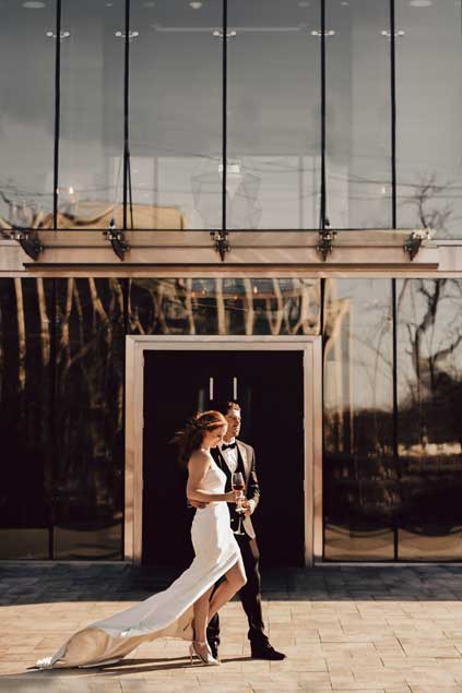 A bride and groom posing outside One10. 