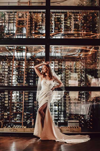 Bride posing in front of the wine cellar glass wall. 