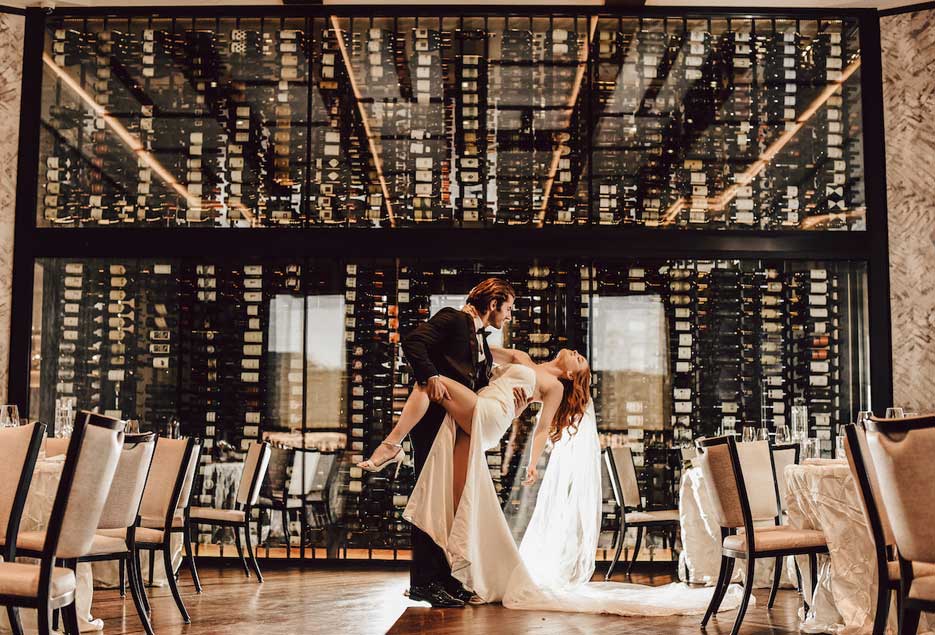 The groom dipping the bride in front of the wine glass wall. 