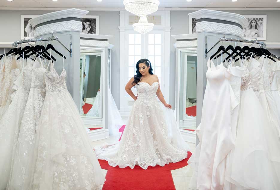 A bride standing in the center of the wedding dressing room between two large mirrors. 