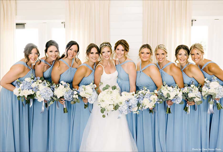 The bride and her bridesmaids in their light power blue dresses posing for a photo. 