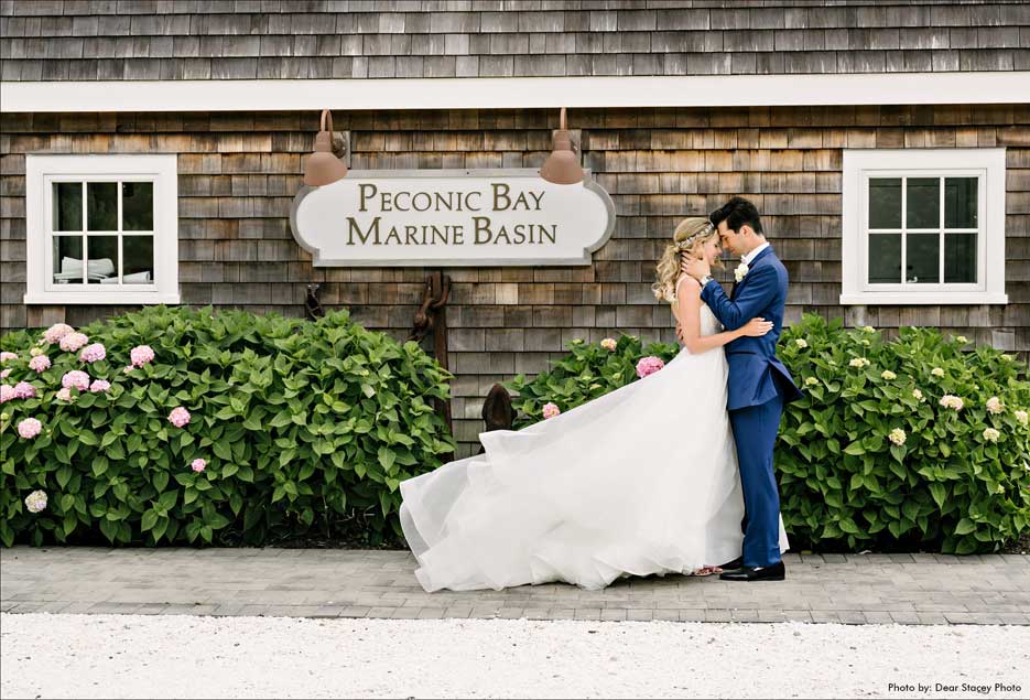 Groom and bride posing in front of the Peconic Bay Yacht Club sign. 