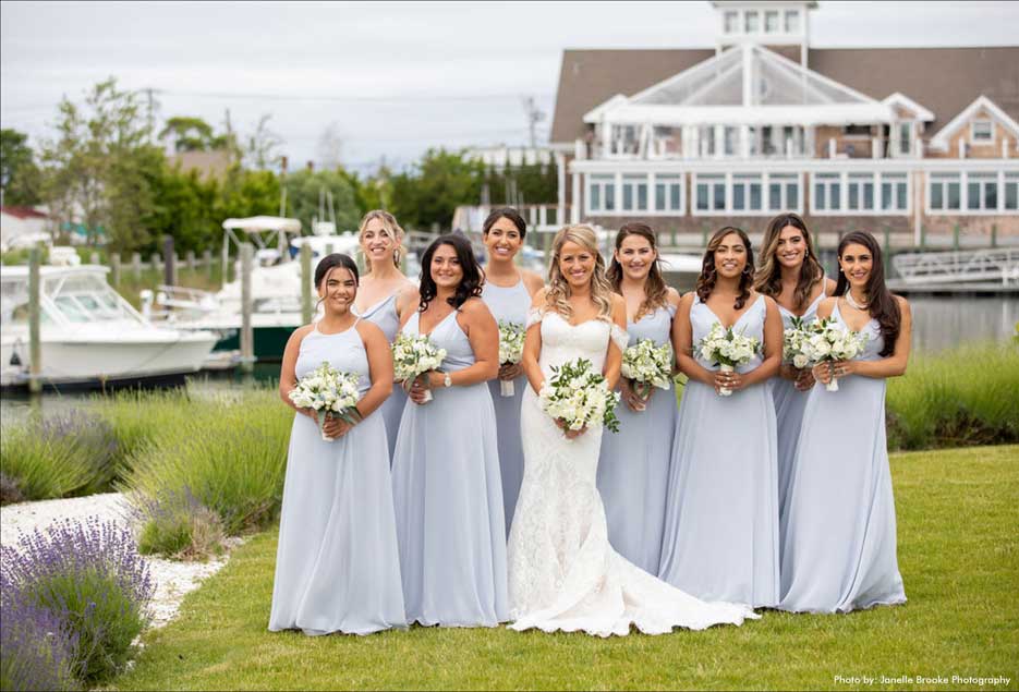 Bride with her bridesmaids outside on the lawn with Peconic Bay Yacht Club in background. 