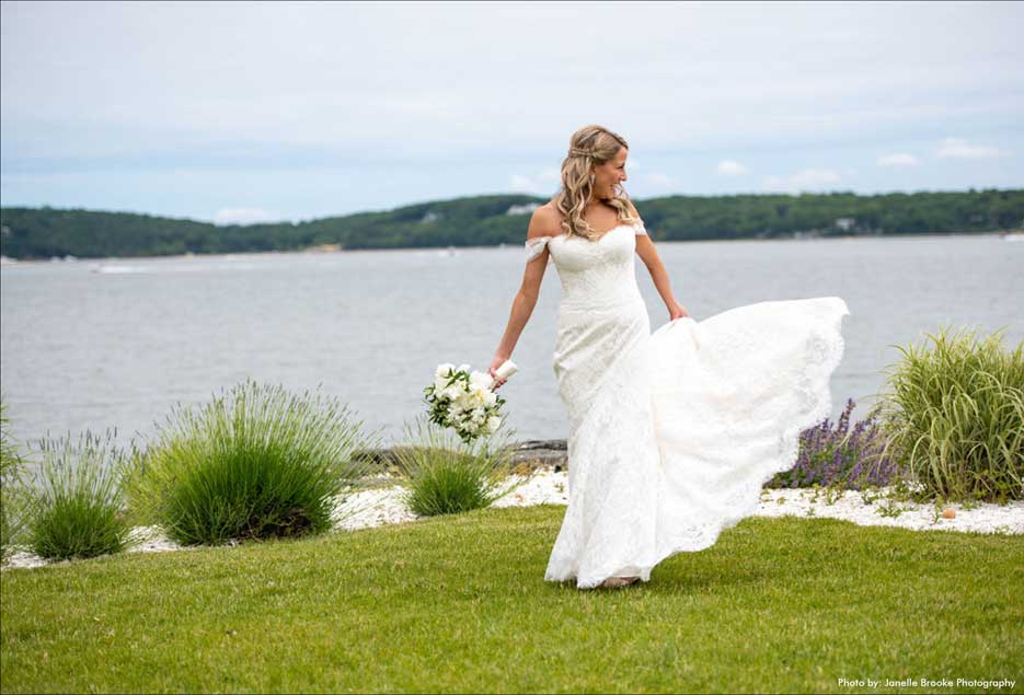 Bride holding a bouquet of flowers  while walking alone along the water. 