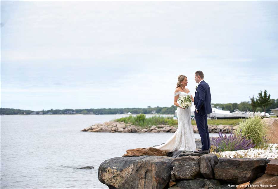 Bride and groom standing on the rocks overlooking the bay. 
