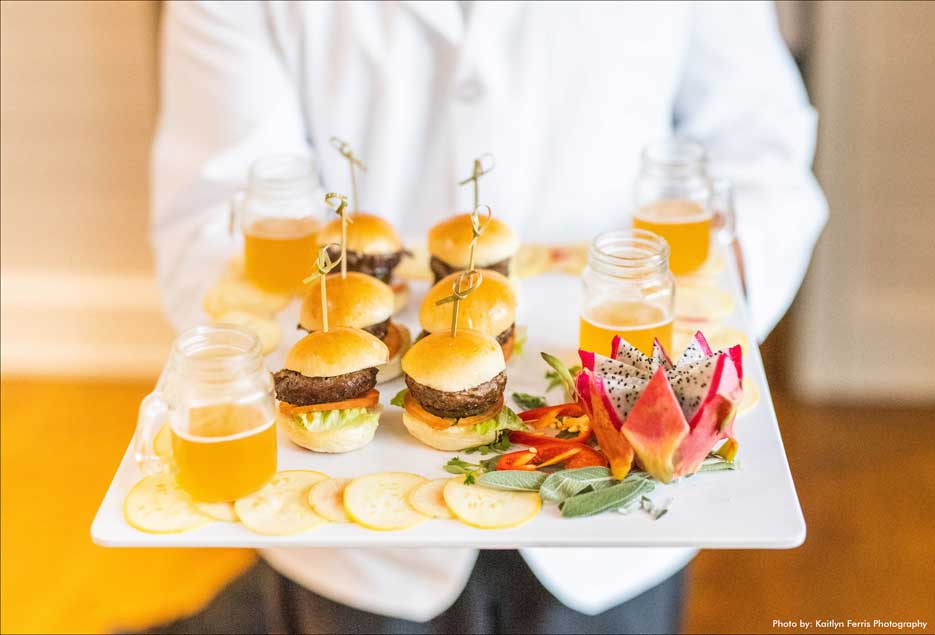 Waiter holding a tray of burger sliders appetizers for the wedding guests. 