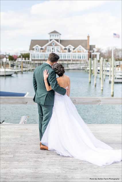 Bride and groom holding each other on the marina as they look back at the Peconic Bay Yacht Club. 