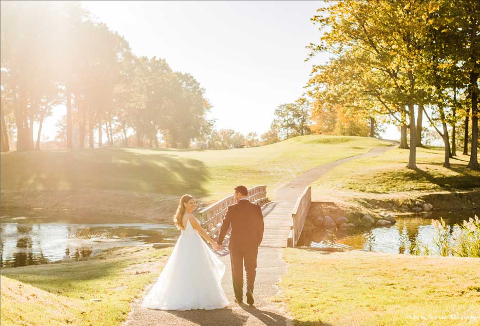 Bride and groom holding hands on golf course at Village Club at Lake Success. 