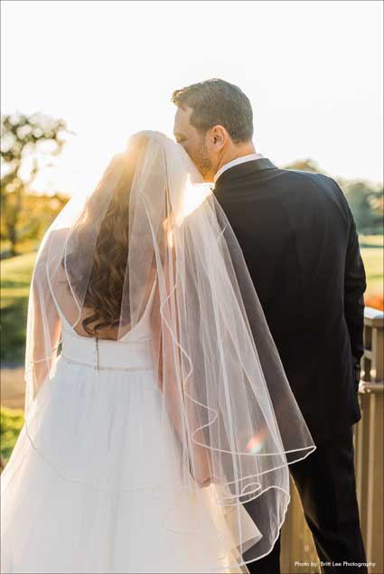 Back view of couple holding hands overlooking the golf course. 