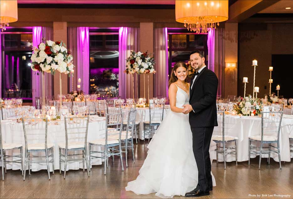 Couple in their wedding reception room with pink uplighting. 