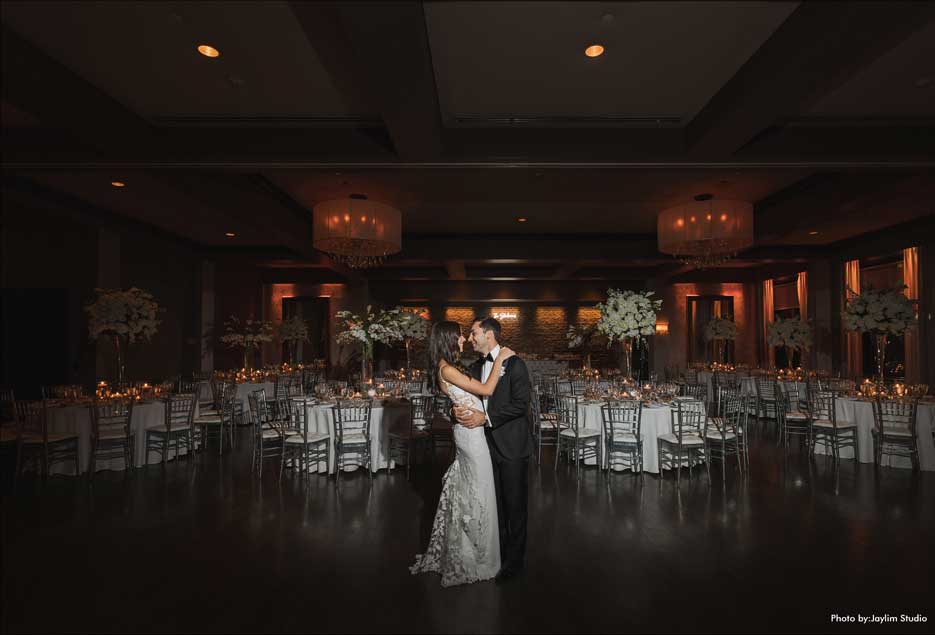 Couple holding each other close while dancing by themselves in their reception room before guest arr