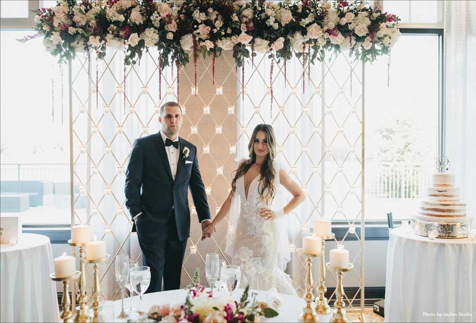 Couple holding hands in front of their decorated wedding table. 