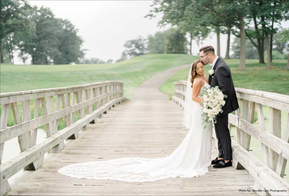 Bride and Groom on bridge posing for wedding photos at The Village Club at Lake Success. 