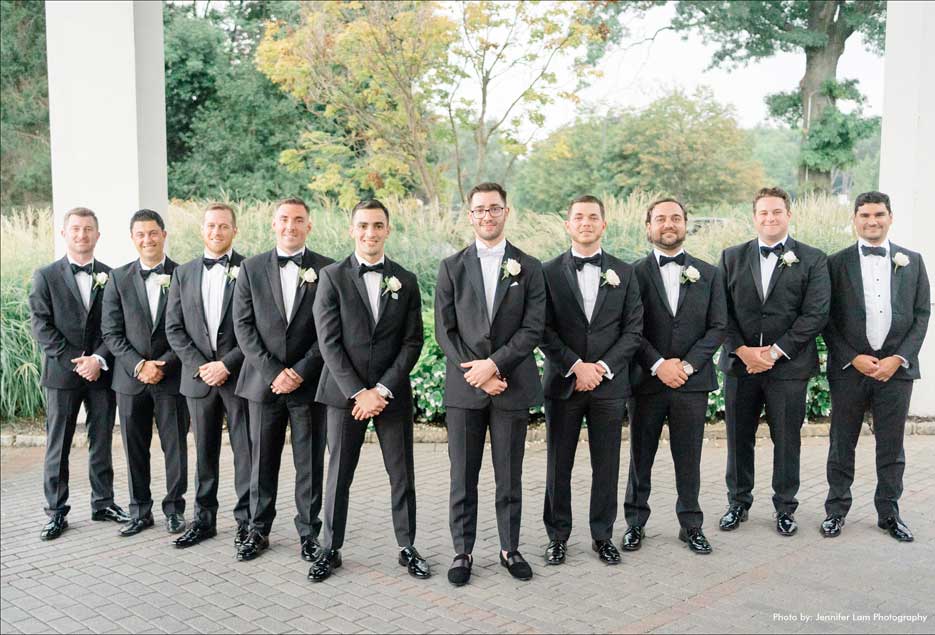 Groomsmen posing for wedding photos in their black tuxedos. 