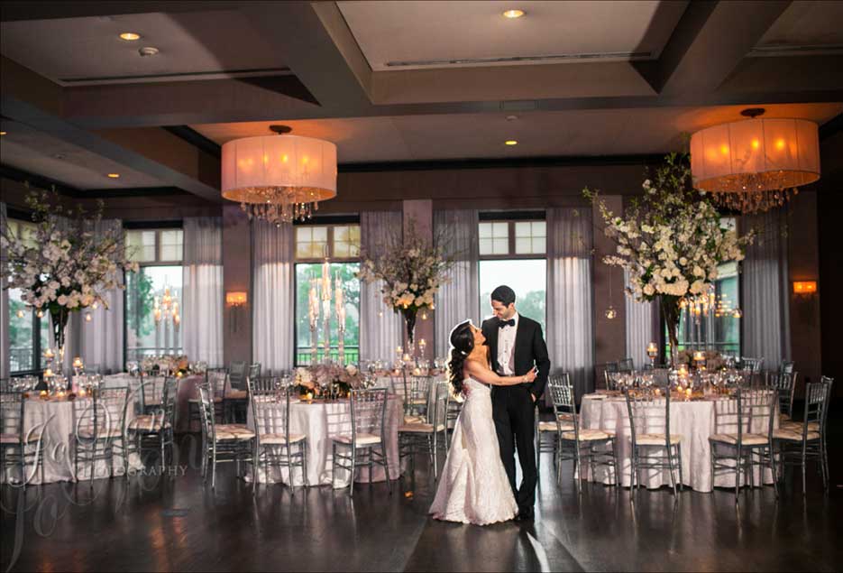 Couple in wedding reception room hugging each other with the lights dim. 