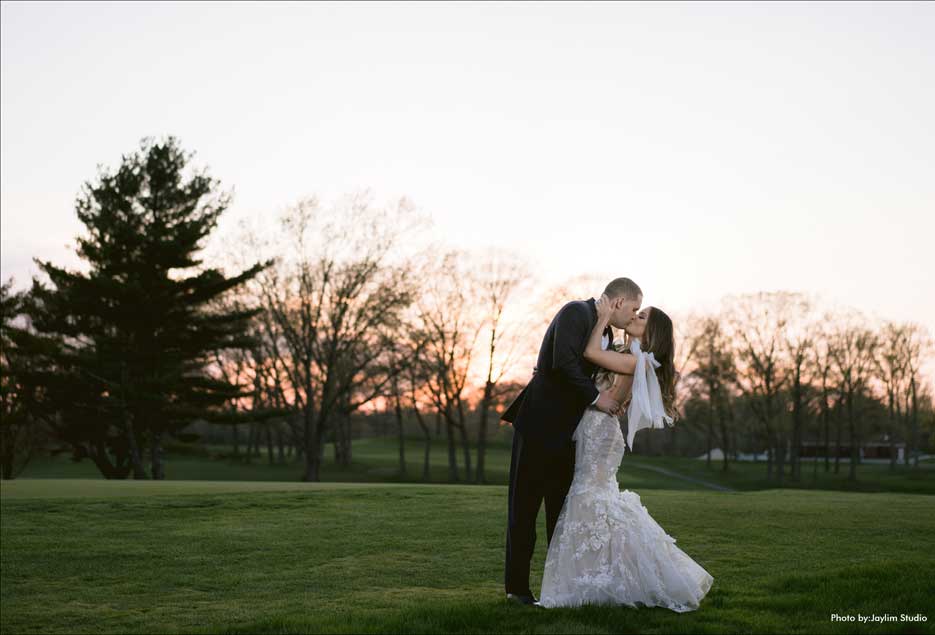 Couple kissing on the golf course at dusk at The Village Club at Lake Success. 