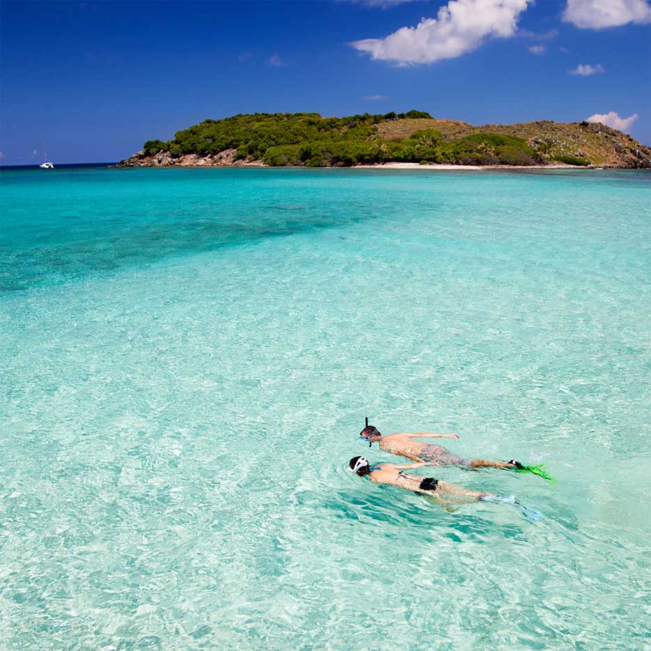 A couple snorkeling in clear blue water. 